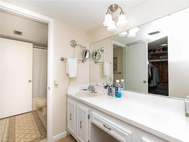 Bathroom with vanity, toilet, a textured ceiling, a shower with curtain, and tile patterned flooring