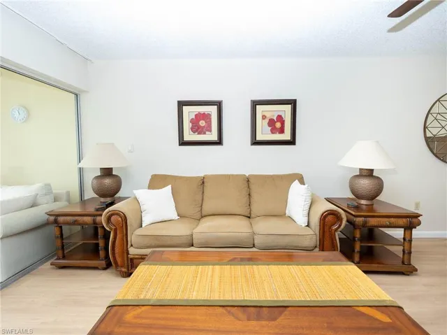 Living room with a textured ceiling, ceiling fan, and light hardwood / wood-style flooring