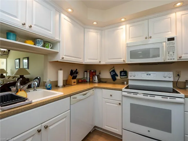 Kitchen with light wood-type flooring, white appliances, white cabinetry, and sink