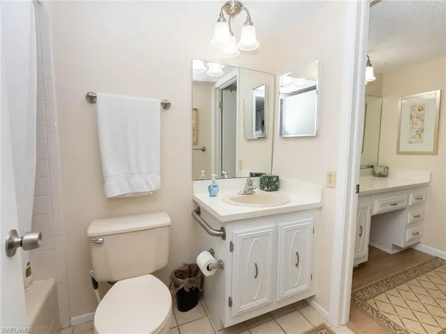 Full bathroom featuring vanity, a textured ceiling, shower / tub combo, tile patterned floors, and toilet