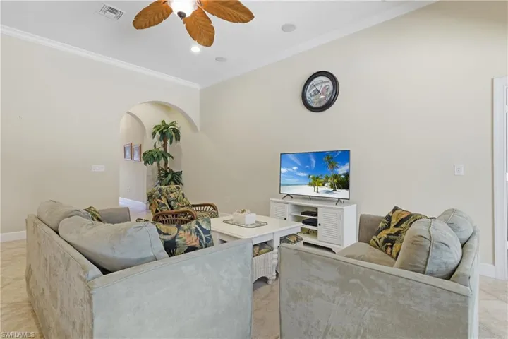 Living area featuring crown molding, a ceiling fan, arched walkways, light tile patterned floors, and recessed lighting