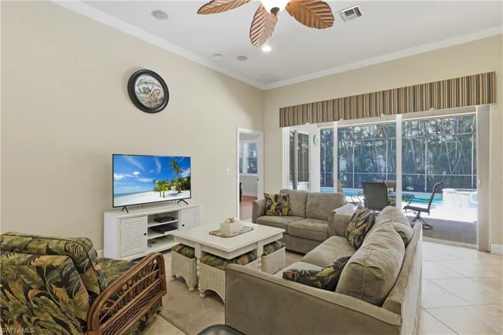 Living room with a sunroom, crown molding, tile patterned flooring, a ceiling fan, and recessed lighting