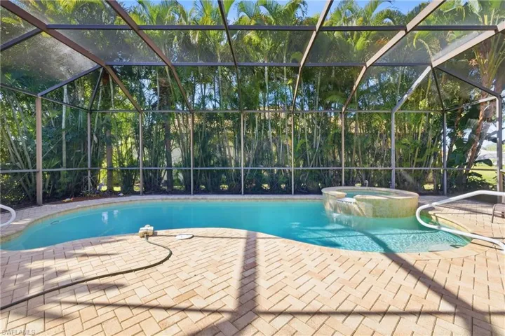 View of swimming pool featuring a lanai, a pool with connected hot tub, a sunroom, and a patio