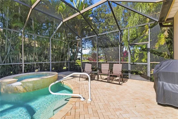 View of swimming pool featuring glass enclosure, area for grilling, a patio, a pool with connected hot tub, and a sunroom