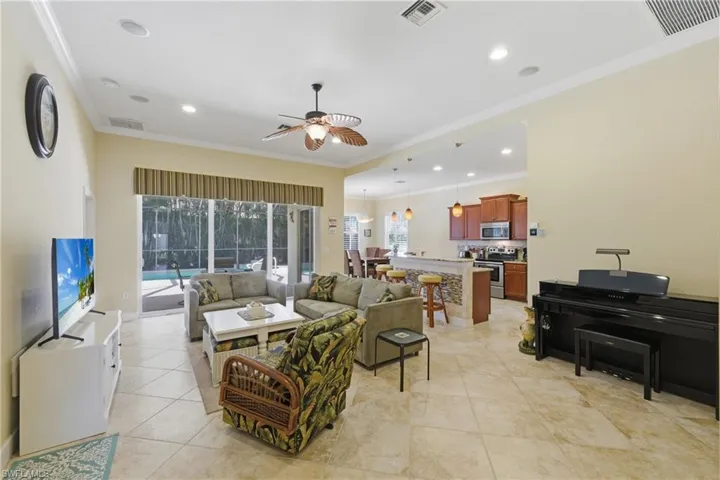 Living area with ornamental molding, a ceiling fan, light tile patterned floors, and recessed lighting