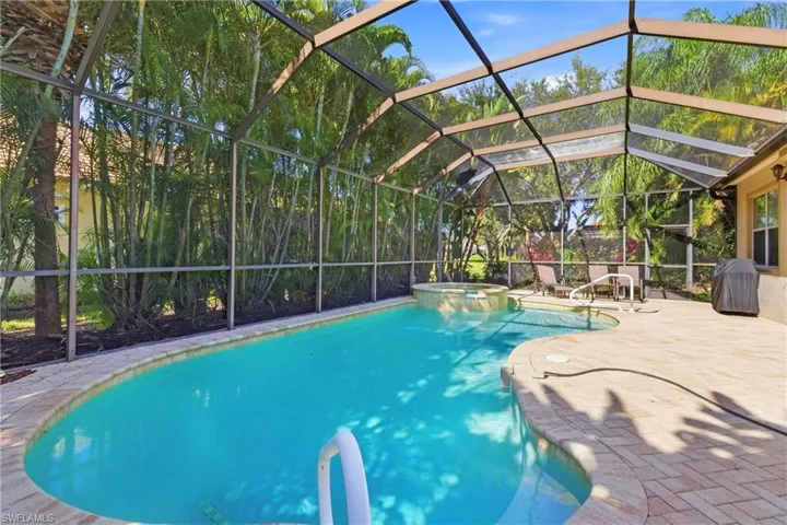 View of swimming pool with a lanai, a pool with connected hot tub, a grill, a patio area, and a sunroom