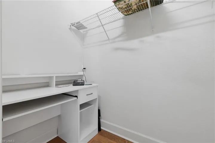 Walk in closet with dark wood-type flooring