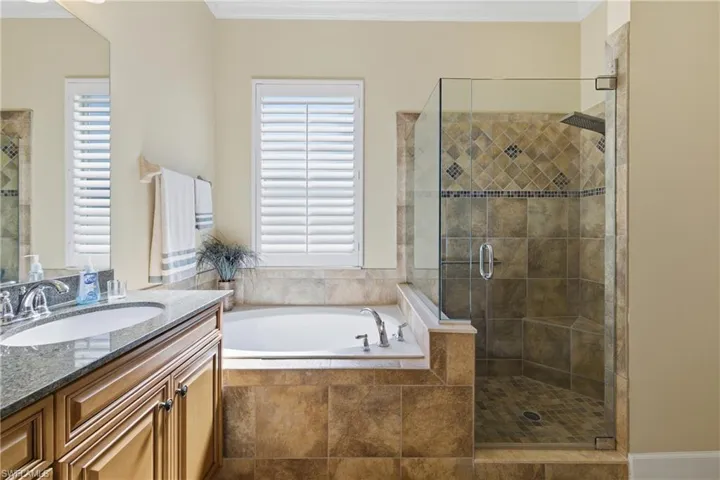 Bathroom with a bath, ornamental molding, vanity, and a shower stall