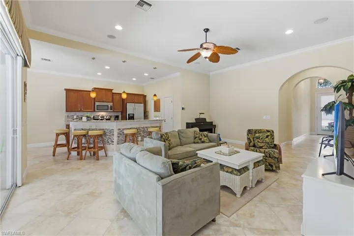 Living area featuring recessed lighting, arched walkways, a ceiling fan, crown molding, and light tile patterned floors