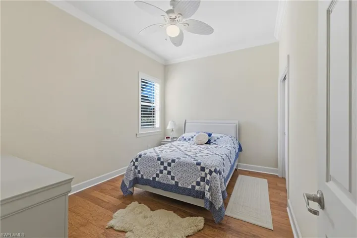Bedroom featuring ornamental molding, wood finished floors, and a ceiling fan