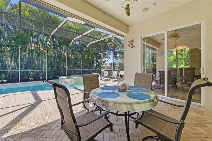View of patio with a lanai, a sunroom, a ceiling fan, and a pool with connected hot tub