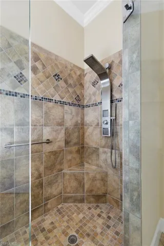 Full bathroom with ornamental molding and tiled shower
