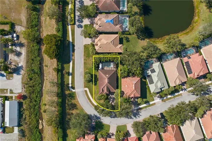 Aerial view of residential area with a large body of water and property parcel outlined