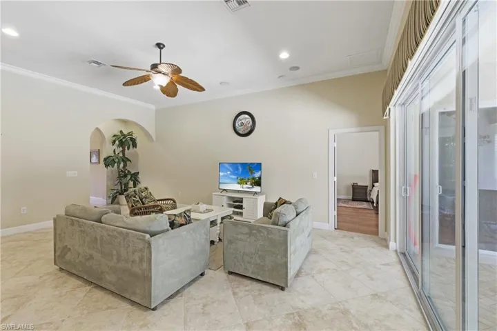 Living room featuring recessed lighting, ornamental molding, ceiling fan, and arched walkways