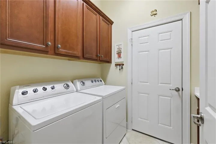 Laundry area with cabinet space, washing machine and dryer, and light tile patterned flooring