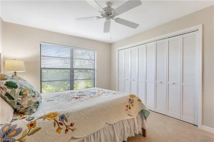 Carpeted bedroom featuring ceiling fan and a closet