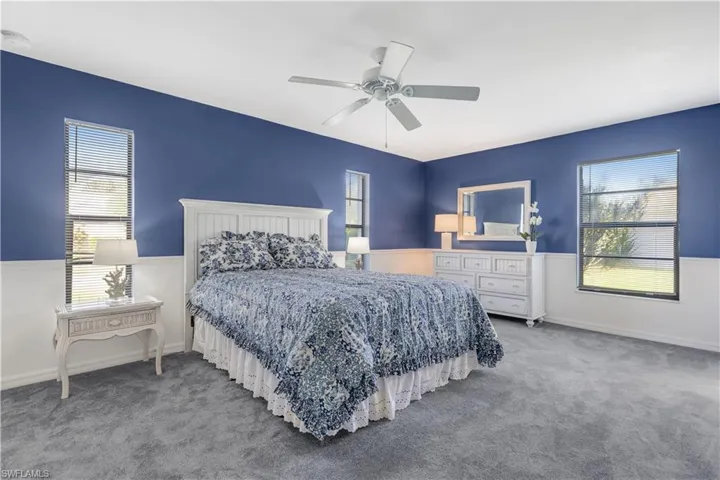 Bedroom featuring light carpet, multiple windows, and ceiling fan