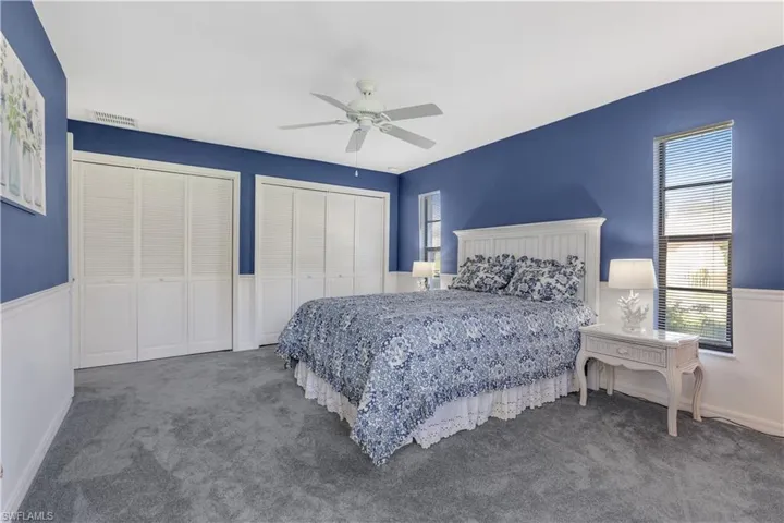 Carpeted bedroom featuring ceiling fan and multiple closets