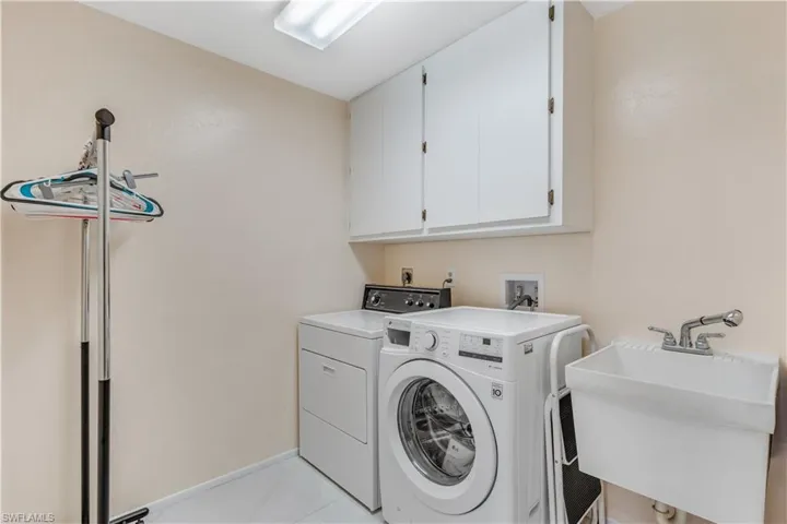 Washroom featuring light tile patterned floors, cabinets, washing machine and dryer, and sink