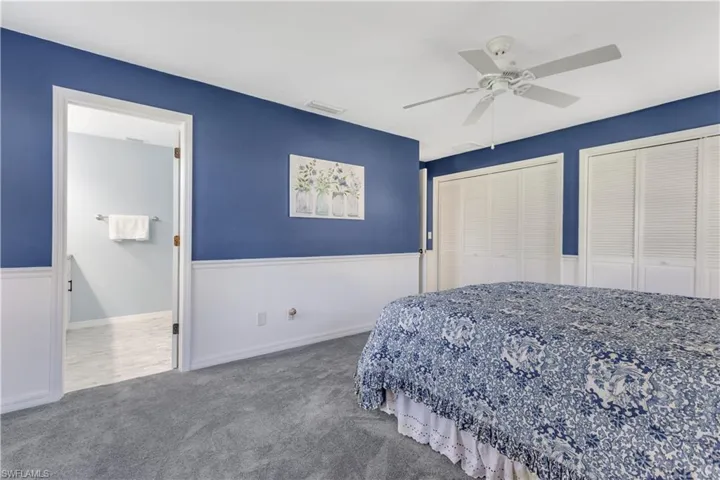 Carpeted bedroom featuring two closets and ceiling fan