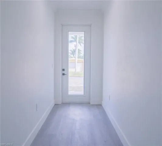 Doorway to outside featuring ornamental molding and wood finished floors