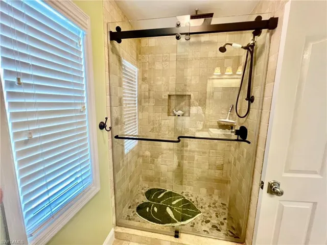 Frameless glass shower door with newly tiled shower.