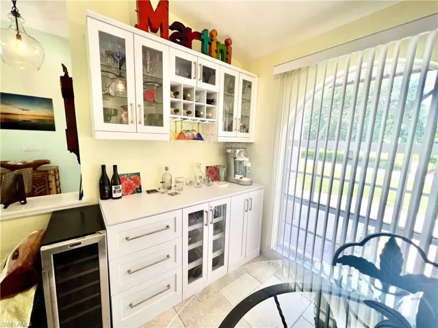 Bar with a beverage cooler and wine storage with glass cabinets.