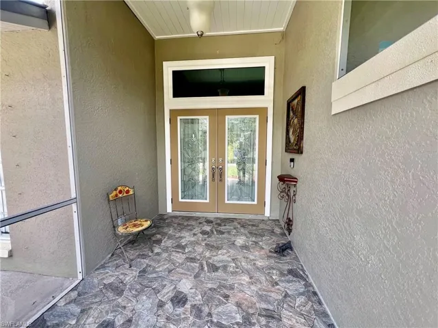 Screened entrance to property with French doors, tile floors and stucco siding