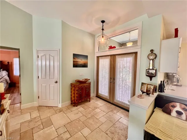 Entrance foyer featuring stone tile flooring, baseboards, and french doors