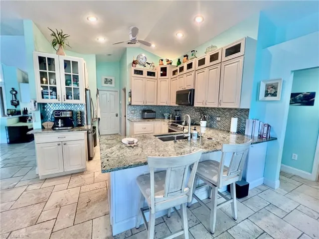 Kitchen featuring a breakfast bar, a sink, backsplash, a coffee bar, and cathedral ceilings.
