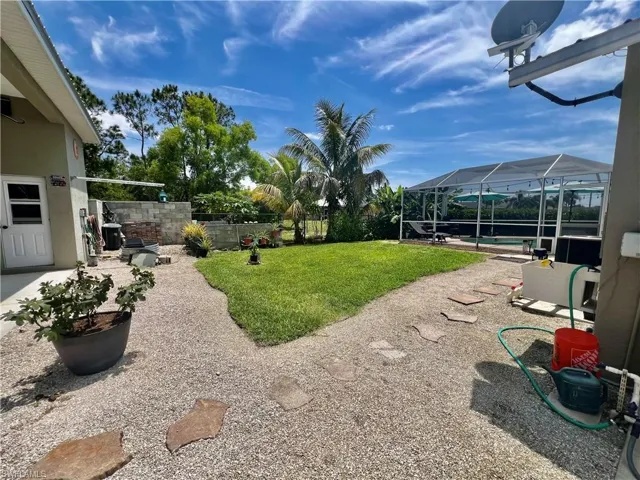 View of nicely landscaped yard with a pool, a patio, a fenced backyard, and screen enclosed pool.