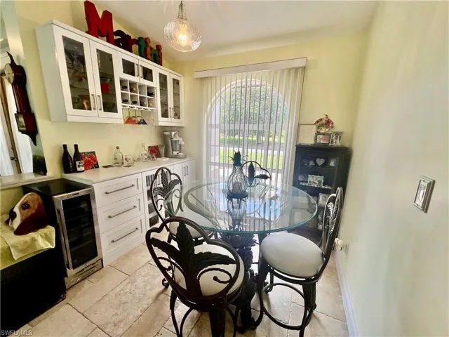 Dining room with travertine tile, beverage cooler, and a bar with wine storage.