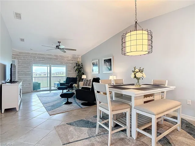 Dining room with vaulted ceiling, light tile patterned flooring, and ceiling fan