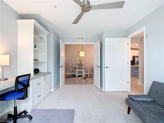 Office area with light carpet, a ceiling fan, and built in desk