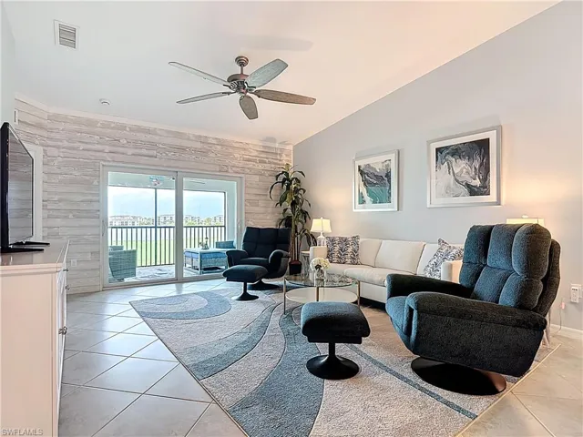 Living area featuring wood walls, light tile patterned flooring, a ceiling fan, and vaulted ceiling