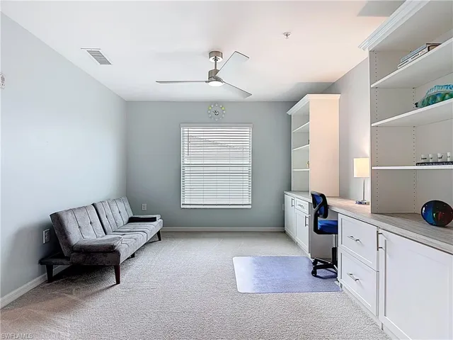 Home office featuring built in study area, light colored carpet, and ceiling fan
