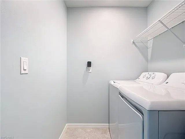 Washroom with separate washer and dryer and light tile patterned floors