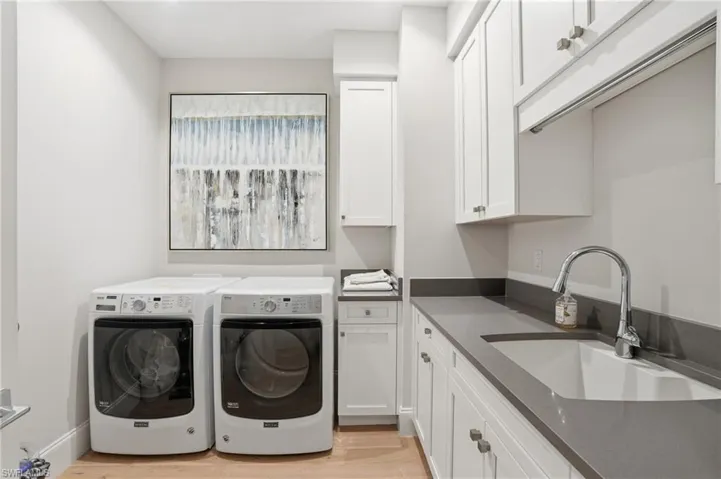 Laundry room complete with a sink, storage, and high end washer/dryer.