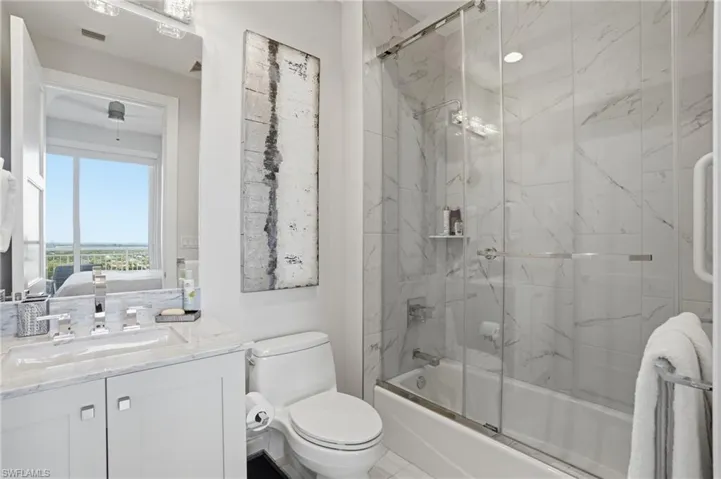 Ensuite guest bath with shower/tub combo and glass doors.
