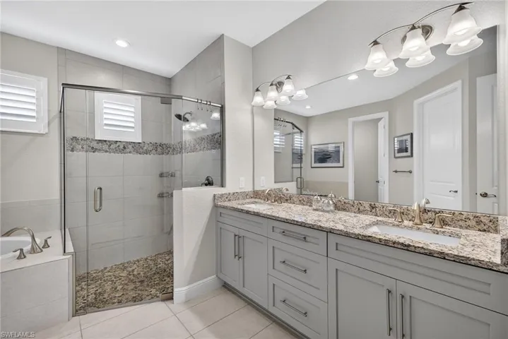 Full bathroom featuring double vanity, a garden tub, a shower stall, and light tile patterned floors
