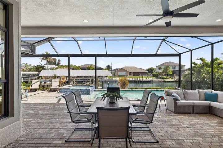 View of lanai with a pool with connected hot tub, dining and lounging areas, large dock, tiki bar and a beautiful water view