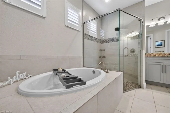 Full bathroom featuring double vanity, a garden tub, a shower stall, and light tile patterned floors