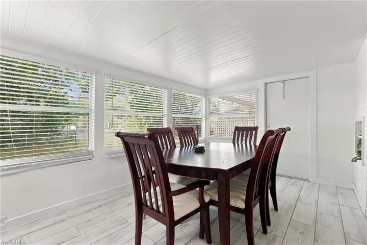 Sunroom featuring plank-style tile flooring, white wood-paneled ceiling, and multiple horizontal windows