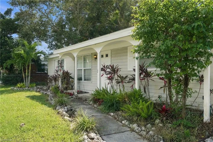 Single-story exterior featuring horizontal siding, a covered front porch with arched supports, and a concrete walkway bordered by rock landscaping