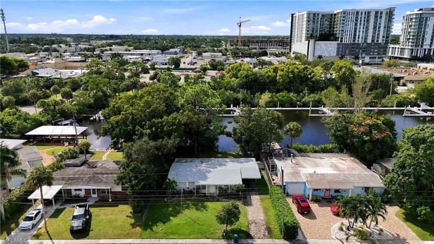 Aerial perspective featuring residential lots with direct canal frontage, paved driveways, and mature landscaping