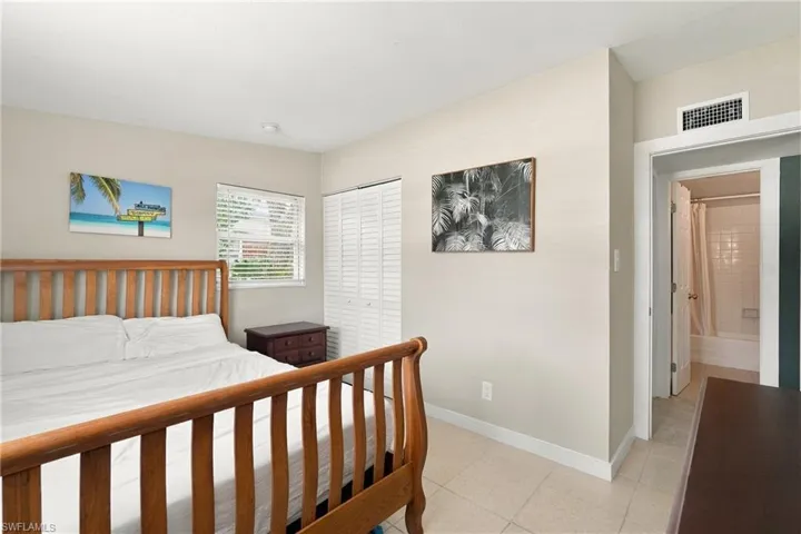 Neutral-toned interior space featuring light-colored tile flooring, white bi-fold closet doors, and horizontal slat window blinds