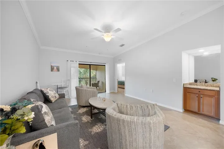 Living room featuring ornamental molding, light tile patterned floors, and a ceiling fan
