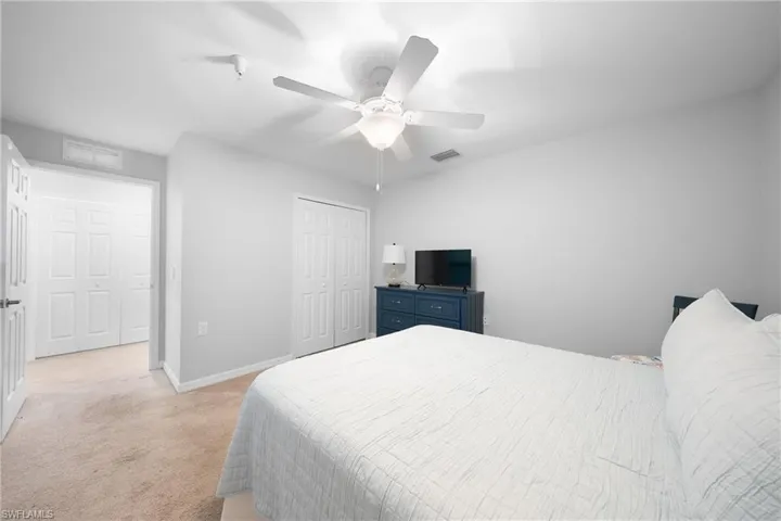 Bedroom with light colored carpet, a ceiling fan, and a closet