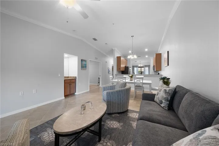 Living room with crown molding, lofted ceiling, a chandelier, recessed lighting, and ceiling fan