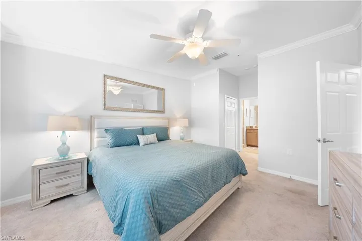 Bedroom with ornamental molding, light carpet, connected bathroom, a closet, and ceiling fan